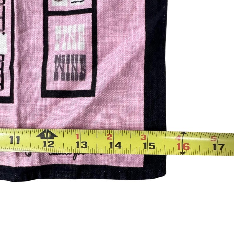 Pu&ograve; includere: Canovaccio da cucina rosa e nero a tema vino. Il canovaccio presenta la parola "WINE" in un design a blocchi. Il canovaccio misura circa 40,6 cm di lunghezza.