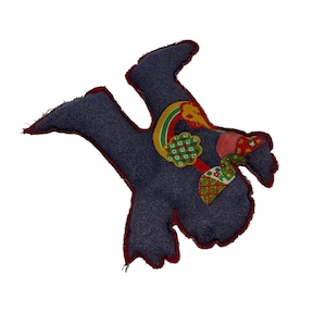 May include: A handmade, whimsical fabric bird-shaped ornament. The bird is made of dark blue denim with red trim and colorful patchwork details. The patchwork includes a rainbow, floral, and geometric patterns.
