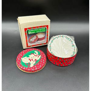 May include: A set of vintage "Purr-fect Notes" stationery. The set includes a cardboard box and two round tins. The tins and box feature a red background with white cat illustrations and green holly accents, perfect for cat lovers.