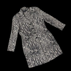 May include: A long-sleeved, button-down coat with a snakeskin pattern in black and off-white. The coat has a notched collar and a tailored fit. The fabric appears to be a woven material. The coat is displayed against a black background.
