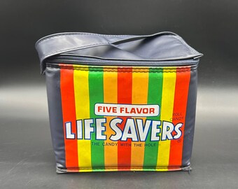 Puede incluir: Una bolsa de almuerzo aislante azul marino con cierre de cremallera y asa. La parte delantera presenta un diseño de rayas verticales de colores con las palabras "FIVE FLAVOR LIFE SAVERS" y "THE CANDY WITH THE HOLE".
