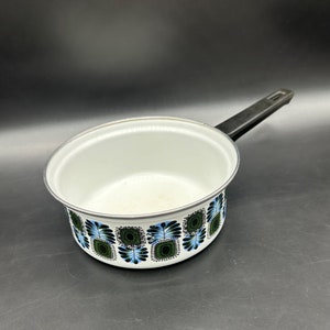 Puede incluir: Cacerola de esmalte blanco con asa negra y un patrón geométrico azul y verde alrededor del borde.