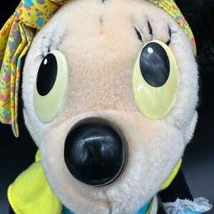 Peut inclure: Un jouet en peluche avec un bandana jaune et bleu, de grands yeux noirs et un nez noir. Le jouet est fait d'un tissu blanc doux.