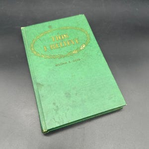 May include: A vintage hardcover book titled "This I Believe" by William B. Ochs. The book has a green cover with gold lettering and a decorative wreath design. The book is slightly worn, showing signs of age.