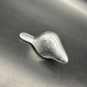 May include: A silver, abstract, bird-shaped sculpture. The sculpture is smooth and has a rounded, organic form.