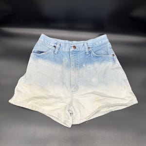 May include: Light blue denim shorts with a faded white ombre effect. The shorts have a high waist and five pockets.