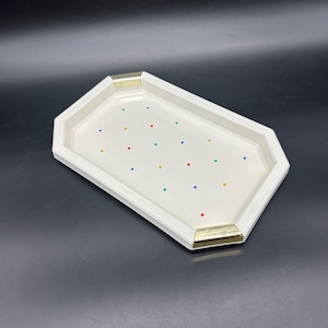 Peut inclure: Un plateau rectangulaire blanc avec un design géométrique et des accents dorés. Le plateau est décoré de pois colorés. Le plateau est fait d'un matériau solide et convient au service ou à l'exposition.