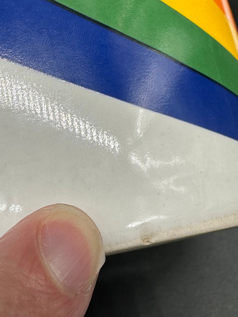 May include: A white ceramic bowl with a rainbow design. The bowl has a blue, green, yellow, and orange stripe pattern.