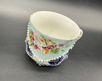 Taza antigua alemana de porcelana con diseño floral pintado a mano, flores azules, blancas y moradas.
