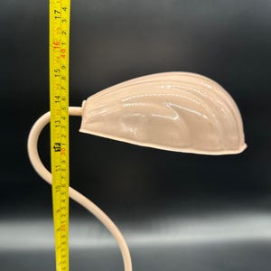 K&ouml;nnte beinhalten: Eine Vintage-Schreibtischlampe mit cremefarbenem, muschelf&ouml;rmigem Schirm. Der gebogene Arm und der Sockel der Lampe sind ebenfalls cremefarben. Die Lampe misst etwa 38 cm in der H&ouml;he. Die Lampe steht vor einem dunklen Hintergrund.