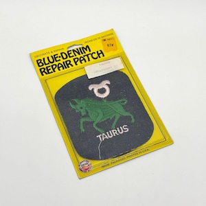 May include: A blue denim repair patch with a green Taurus bull design and the word "TAURUS" embroidered in white. The patch is on a yellow and blue cardboard backing with the text "BLUE-DENIM REPAIR PATCH".