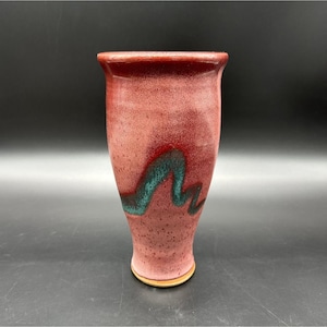 Peut inclure: Un vase en céramique fait à la main avec un extérieur rouge moucheté et un motif de vague turquoise. Le vase a un dessus évasé et une base arrondie. La poterie est une œuvre d'art unique.