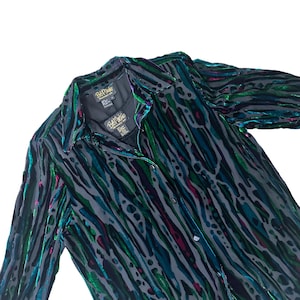 May include: A long-sleeved, black velvet shirt with a green, blue, and pink abstract print. The shirt has a button-up front and a collar. The shirt has the text "Bali Maya" on the label.
