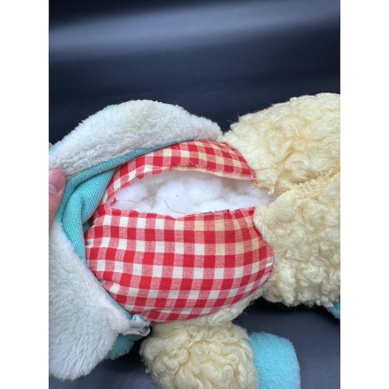 Peut inclure: Un animal en peluche partiellement d&eacute;mont&eacute;, avec un motif &agrave; carreaux rouges et blancs &agrave; l'int&eacute;rieur. L'ext&eacute;rieur pr&eacute;sente une mati&egrave;re duveteuse de couleur cr&egrave;me, avec des accents bleus et blancs. Le jouet semble manquer de rembourrage.