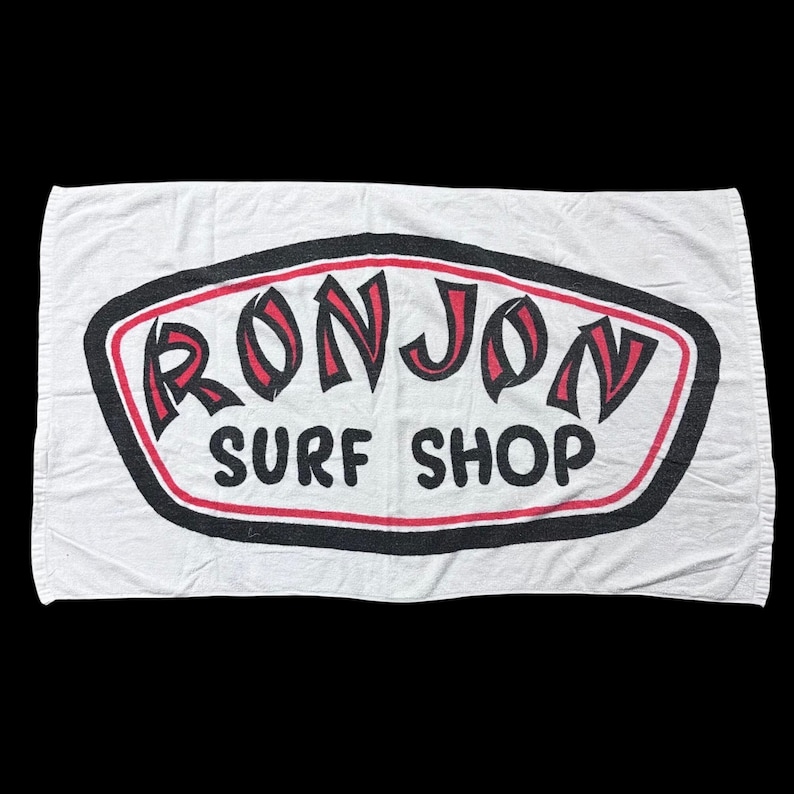 Op de afbeelding: Een witte keramische mok met een zwart handvat en de tekst "But First, Coffee" in een vetgedrukte, zwarte letter. De mok staat op een houten oppervlak. De mok is ongeveer 10 cm hoog.