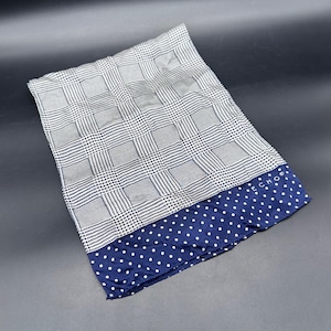 Puede incluir: Un pañuelo plegado con un estampado de cuadros en blanco y negro y un borde azul marino con lunares. La palabra "ECHO" está impresa en el borde. El pañuelo está hecho de una tela suave y ligera.