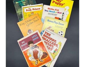 Könnte beinhalten: Eine Sammlung von acht Kinderbüchern mit bunten Umschlägen, die Illustrationen von Tieren, einem Froschkönig, einer Katze und einem Fußballspieler zeigen. Die Titel lauten: "Monster der See", "Der Froschkönig", "König Midas und die goldene Berührung", "Mein Welpe", "Hallo, Katze, du brauchst einen Hut", "Norman spielt Fußball", "Der Größte, der Kleinste, der Kleinste, der Kleinste" und "Großes Pferd, kleines Pferd".