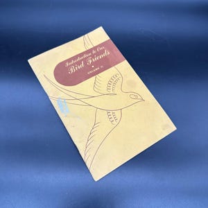 May include: A vintage book titled "Introduction to Our Bird Friends" with a brown cover and a stylized illustration of a bird in flight. The book is volume II.