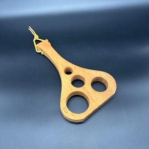 May include: Wooden tool with a handle and four circular cutouts of different sizes. The tool is labeled with the numbers 60, 52, 47, and 32.