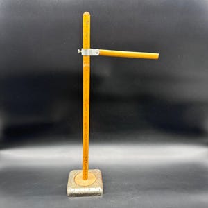 May include: A vintage wooden height gauge with a metal base. The gauge has a vertical ruler marked in inches and a horizontal arm. The wood is a light yellow color, and the metal base is square.