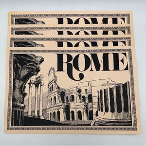 May include: Set of four beige placemats with a black and white illustration of the Colosseum in Rome, Italy. The word "ROME" is printed in large black letters on each placemat.