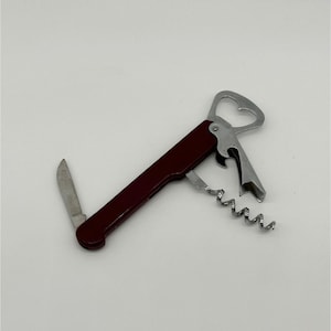 May include: A multi-tool wine opener with a burgundy handle. The tool includes a corkscrew, bottle opener, and small knife. The bottle opener has a heart-shaped design.