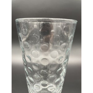 May include: A clear glass drinking glass with a textured surface of small circles.