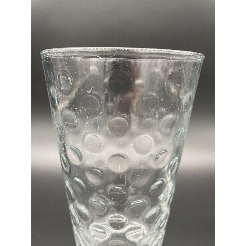 May include: A clear glass drinking glass with a textured surface of small circles.