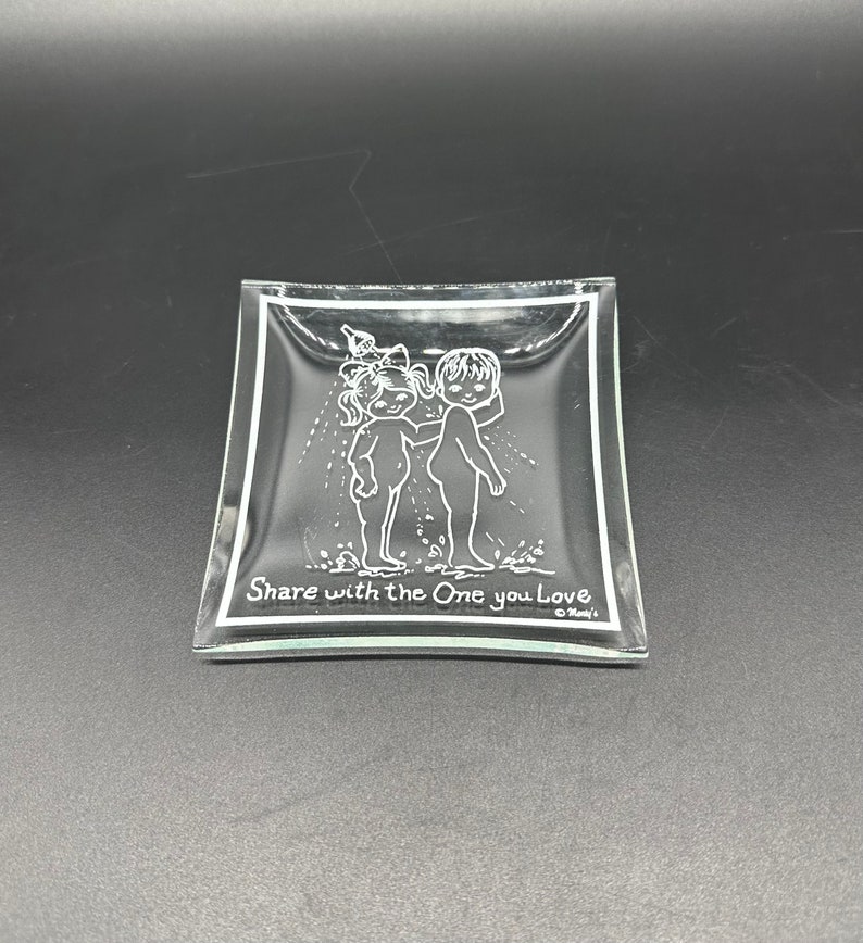 May include: A clear glass dish with a raised design of two children holding a watering can. The dish has a white border and the text "Share with the One you Love" at the bottom.