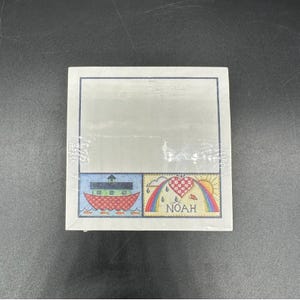Puede incluir: Un juego de papel de notas en caja con un diseño decorativo. El diseño incluye una colorida ilustración del Arca de Noé, un arcoíris y un corazón. La palabra "NOAH" está impresa debajo del corazón. El papel está envuelto en plástico transparente.