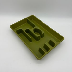 May include: A green plastic utensil holder with five compartments. The holder is designed to hold forks, spoons, and knives.