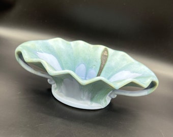May include: A blue and green ceramic bowl with two handles. The bowl has a wavy rim and a unique glaze.