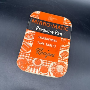 May include: Vintage Mirro-Matic Pressure Pan recipe booklet. The cover is orange and black with the words "Mirro-Matic Pressure Pan" and "Recipes". The booklet features illustrations of various dishes and a checkered pattern.
