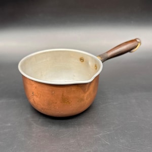 Cacerola de cobre vintage con mango de madera, utensilios de cocina rústicos, cucharón, boquilla para verter.