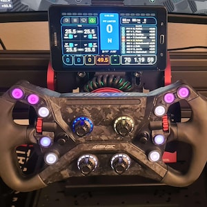 Könnte beinhalten: Ein Rennsimulator-Lenkrad mit einem Carbonfaser-Design, das mehrere Tasten und Drehregler aufweist. Ein Tablet zeigt Renndaten an, das über dem Lenkrad montiert ist. Das Lenkrad hat einen schwarzen Griff und ist mit lila und weißen Lichtern beleuchtet. Das Tablet zeigt den Text "SAMSUNG".