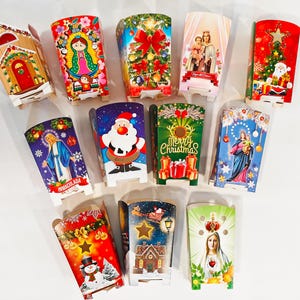 May include: A collection of colorful, decorative paper lanterns with various religious and Christmas-themed designs. The lanterns feature images of Santa Claus, the Virgin Mary, Christmas trees, and festive decorations. Each lantern has a small wooden base.