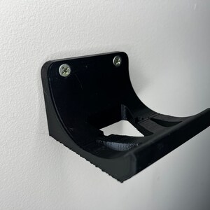 Peut inclure: Support mural en plastique noir avec deux vis. Le support est con&ccedil;u pour tenir un petit objet, comme un t&eacute;l&eacute;phone ou une brosse &agrave; dents.