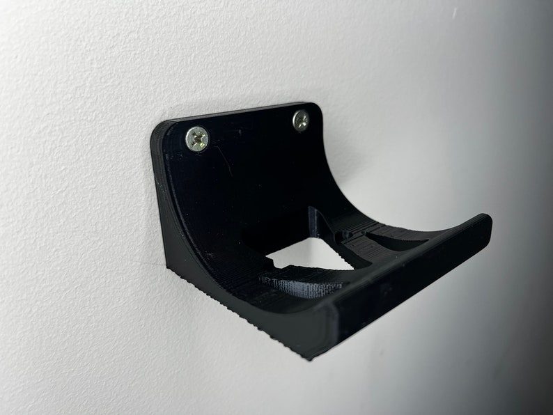 Peut inclure: Support mural en plastique noir avec deux vis. Le support est con&ccedil;u pour tenir un petit objet, comme un t&eacute;l&eacute;phone ou une brosse &agrave; dents.