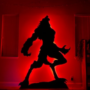 May include: A black silhouette of a werewolf howling at the moon, illuminated with red LED lights against a red wall.