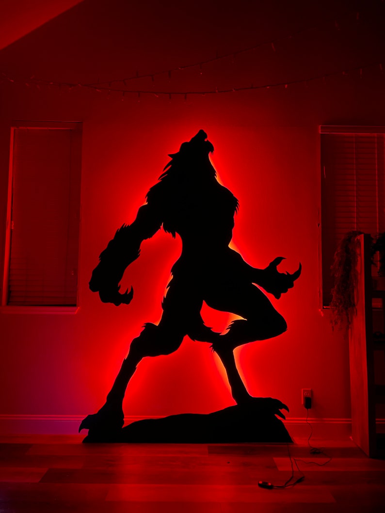 May include: A black silhouette of a werewolf howling at the moon, illuminated with red LED lights against a red wall.