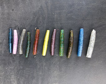 May include: Assortment of 13 different colored soft plastic fishing lures. The lures are about 3 inches long and have a speckled pattern.