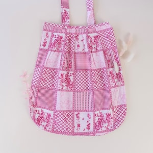 Könnte beinhalten: Eine rosa und weiße Patchwork-Tragetasche mit floralen und geometrischen Mustern. Die Tasche hat zwei lange Henkel.