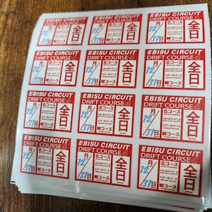 May include: A stack of red and white stickers with the text "Ebisu Circuit Drift Course" and a calendar icon with the date "12/31". The stickers also have the text "全日" which means "all day" in Japanese.