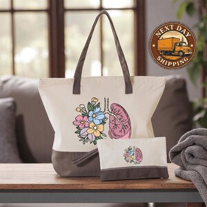 a white tote bag with a floral design and a smaller bag with a similar floral design, both placed on a wooden surface.