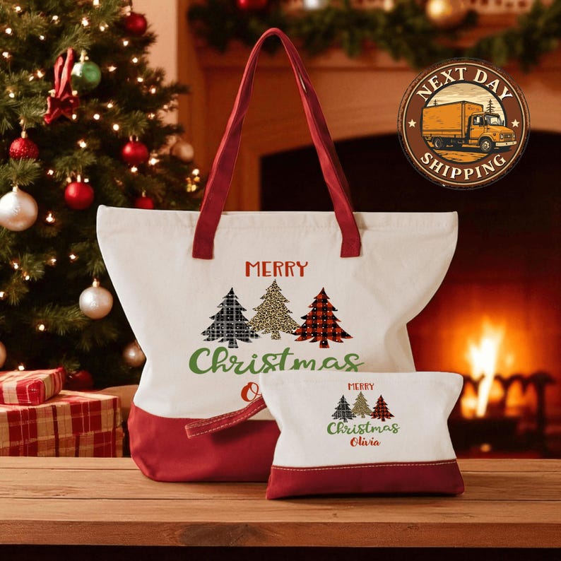 A large white tote bag with a red trim and a smaller red bag with a Christmas tree design, both featuring the text "MERRY CHRISTMAS" printed on them, are displayed in front of a decorated Christmas tree.