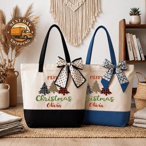 two tote bags with Christmas tree designs and personalized names on them, placed on a woven mat.