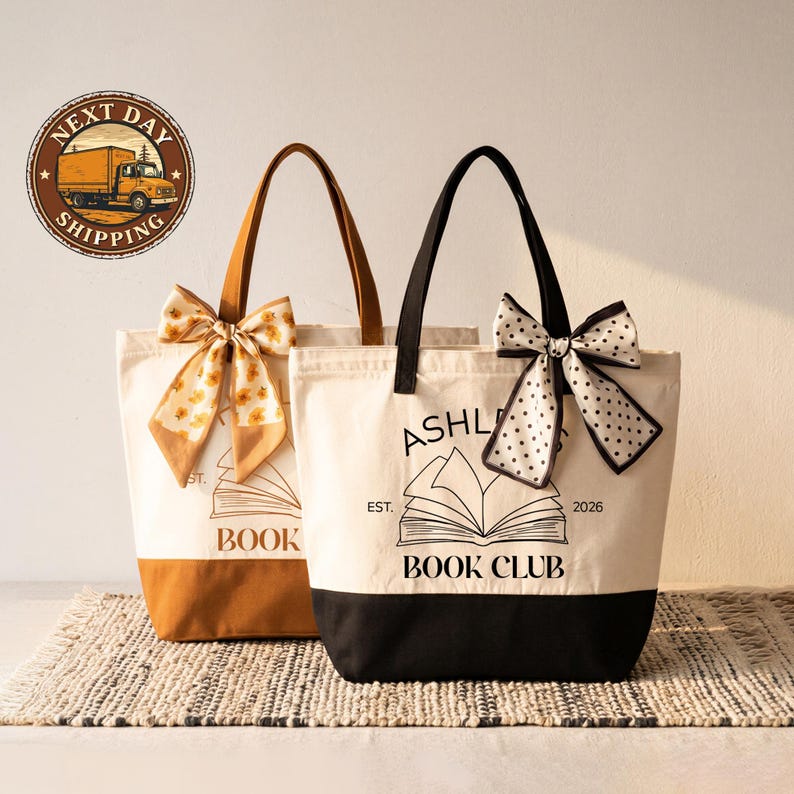 Two tote bags with bows and text, one white and one brown, are displayed on a woven mat.