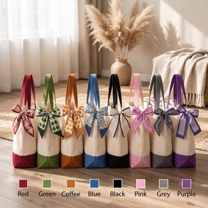 A row of colorful tote bags with bows, each with a different color, displayed on a wooden floor.