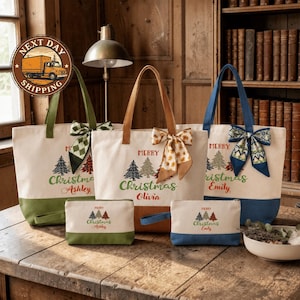 a collection of Christmas-themed tote bags and a small bag, all with personalized names and Christmas tree designs. The tote bags are arranged on a wooden surface, with a lamp and a bookshelf in the background.