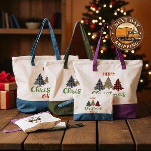 a set of three tote bags with Christmas tree designs, placed on a wooden surface. In the background, there is a Christmas tree and a truck, suggesting a festive setting.